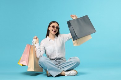 Photo of Excited woman with shopping bags on light blue background