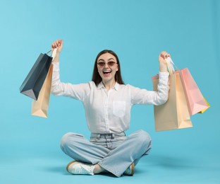 Photo of Excited woman with shopping bags on light blue background