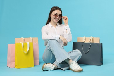 Photo of Positive woman with shopping bags on light blue background