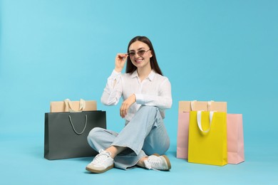 Photo of Positive woman with shopping bags on light blue background