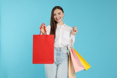 Photo of Positive woman with shopping bags on light blue background