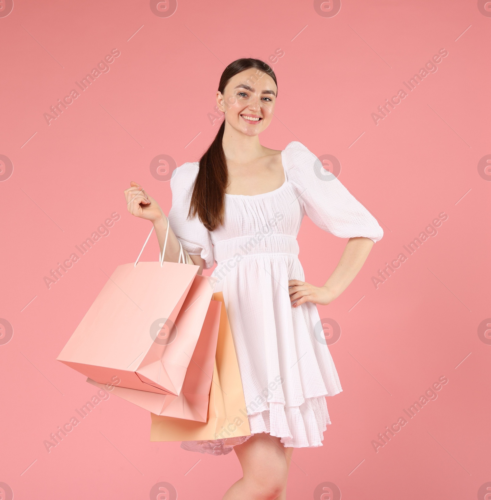 Positive woman with shopping bags on light pink background Photo of Positive woman with shopping bags on light pink background