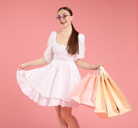 Photo of Positive woman with shopping bags on light pink background
