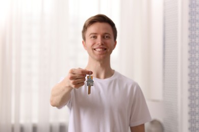 Photo of Happy man with house keys indoors, selective focus
