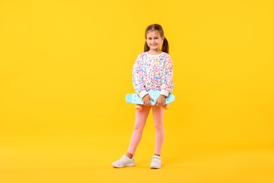 Photo of Little girl with penny board on yellow background