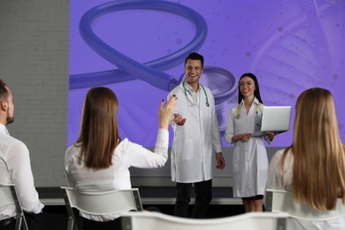 Image of Healthcare professionals giving lecture in conference room using video projector. Illustration on projection screen