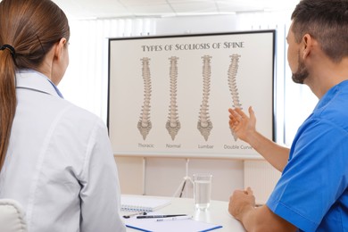 Image of Doctors using video projector during conference about scoliosis indoors. Illustrations on projection screen