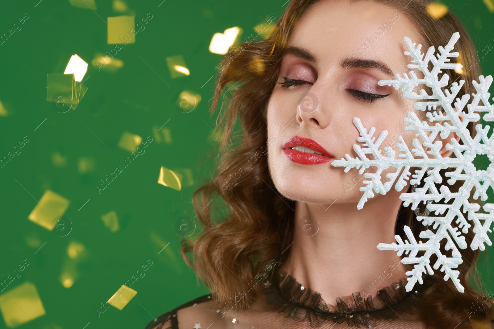 Woman with perfect makeup holding decorative snowflake under falling confetti on green background, space for text. Christmas celebration Image of Woman with perfect makeup holding decorative snowflake under falling confetti on green background, space for text. Christmas celebration