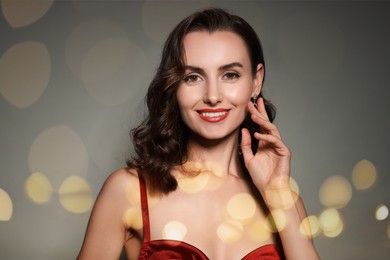 Image of Beautiful woman with perfect makeup and blurred lights on grey background, bokeh effect