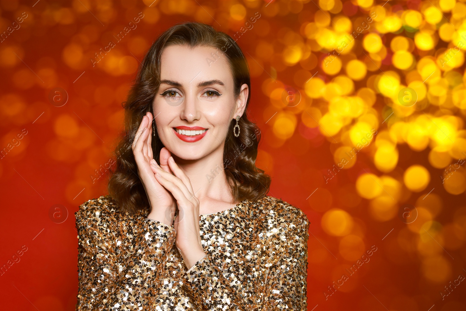 Smiling woman with perfect makeup on red background with blurred lights, bokeh effect Image of Smiling woman with perfect makeup on red background with blurred lights, bokeh effect