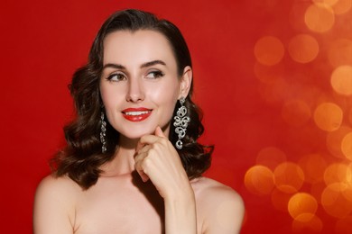 Image of Smiling woman with perfect makeup on red background, bokeh effect