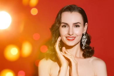 Image of Smiling woman with perfect makeup on red background, bokeh effect