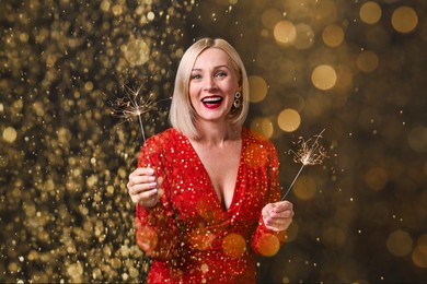 Image of Smiling woman with sparklers celebrating Christmas on black background, bokeh effect