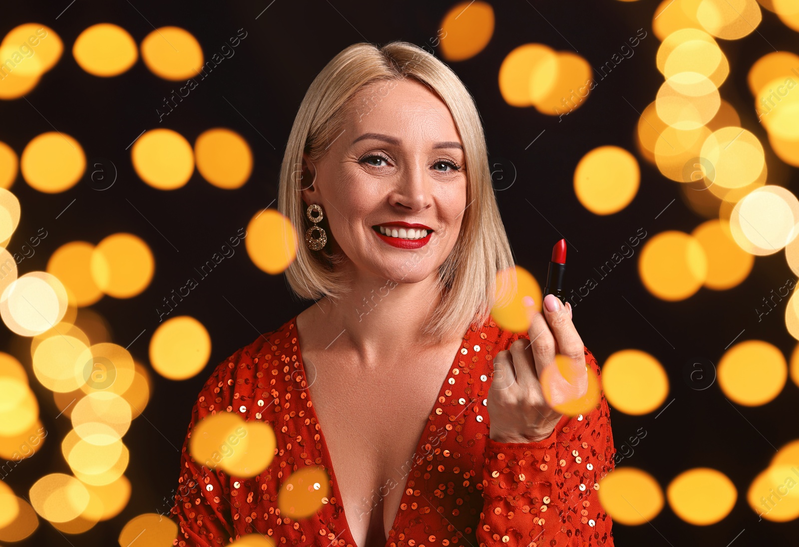 Smiling woman with red lipstick on black background, blurred lights. Bokeh effect Image of Smiling woman with red lipstick on black background, blurred lights. Bokeh effect