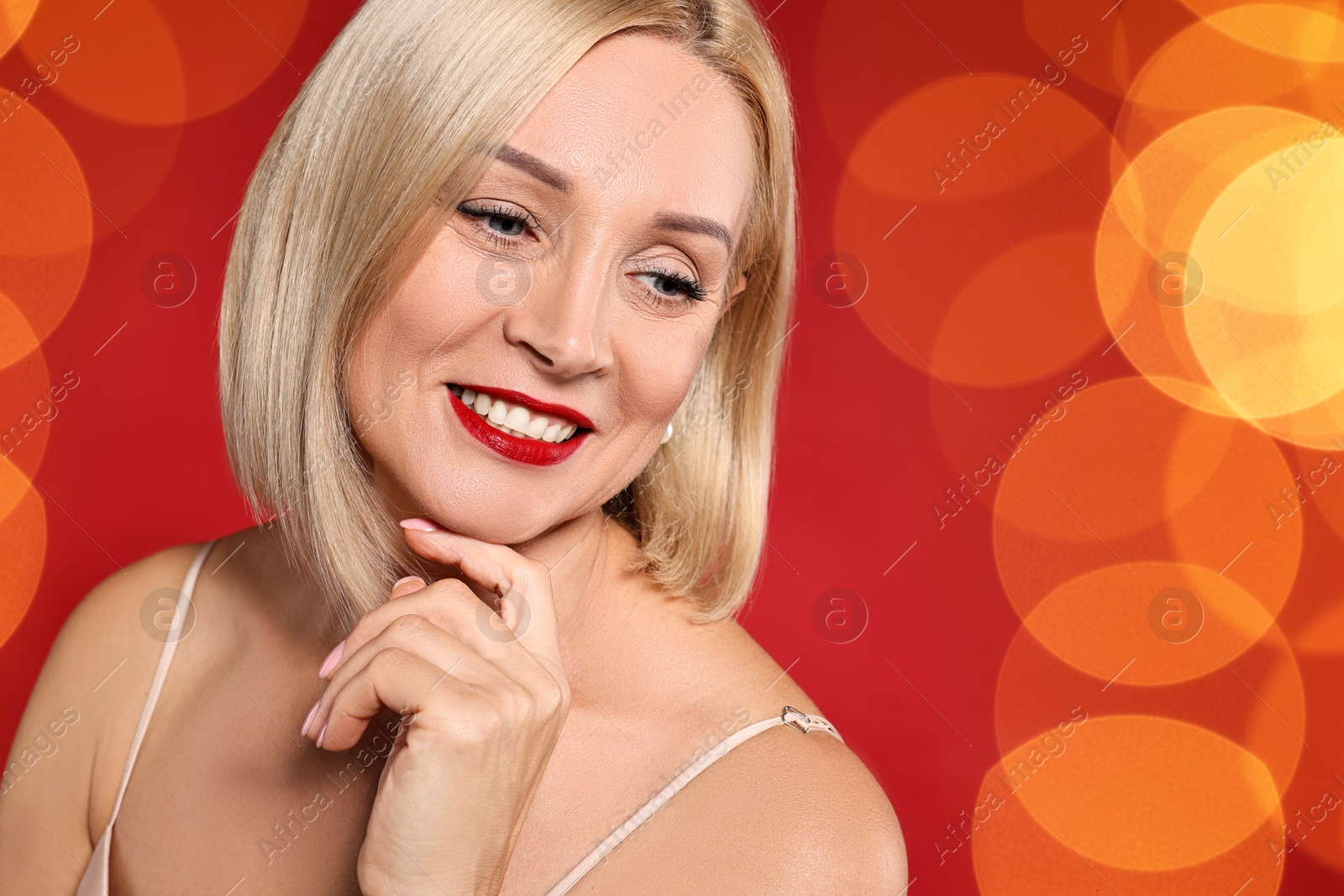 Smiling woman with perfect makeup on red background, blurred lights. Bokeh effect Image of Smiling woman with perfect makeup on red background, blurred lights. Bokeh effect