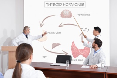 Image of Healthcare professionals giving lecture about thyroid hormones in conference room using video projector. Illustrations on projection screen