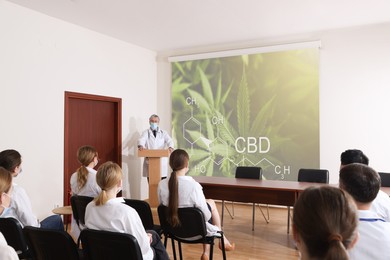 Image of Healthcare professional giving lecture about CBD in conference room using video projector. Illustration on projection screen