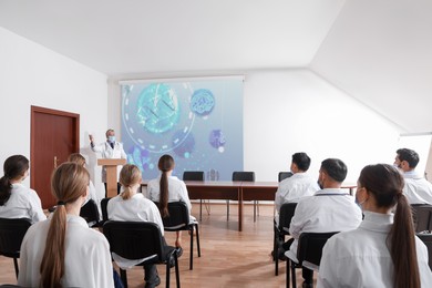 Image of Healthcare professional giving lecture about DNA in conference room using video projector. Illustration on projection screen