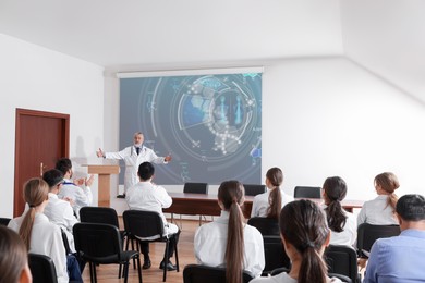 Image of Healthcare professional giving lecture about DNA in conference room using video projector. Illustration on projection screen