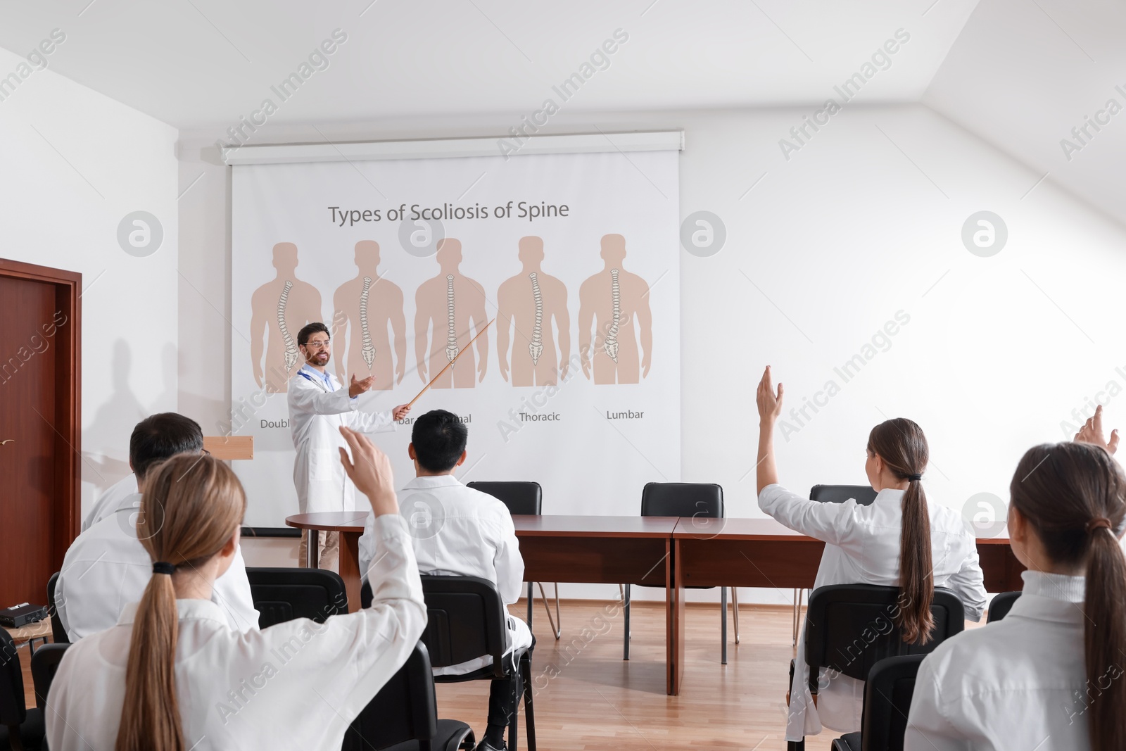 Healthcare professional giving lecture about scoliosis in conference room using video projector. Illustrations on projection screen Image of Healthcare professional giving lecture about scoliosis in conference room using video projector. Illustrations on projection screen