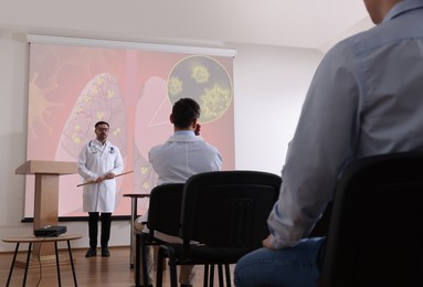 Image of Healthcare professional giving lecture about lung diseases in conference room using video projector. Illustration on projection screen