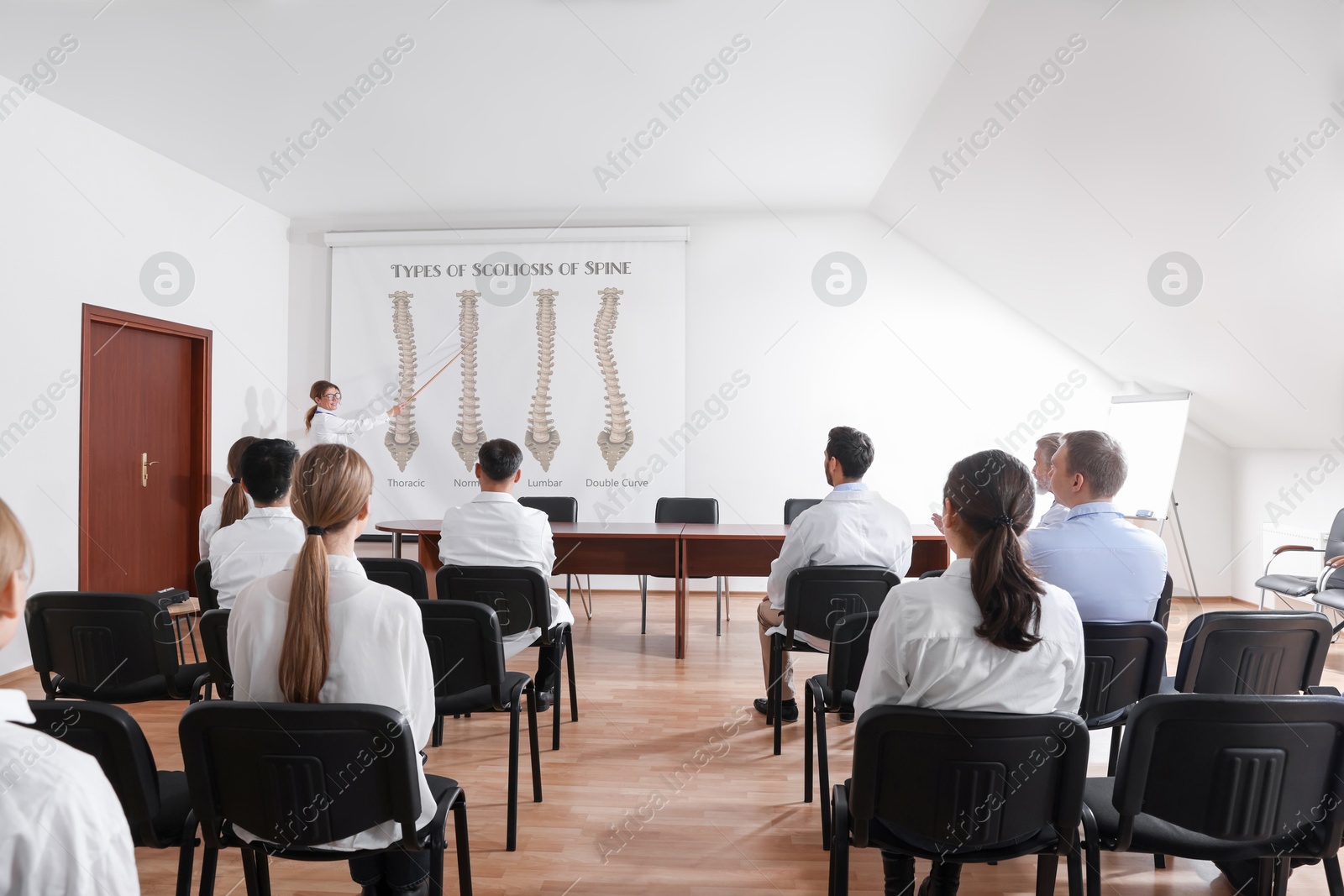 Healthcare professional giving lecture about scoliosis in conference room using video projector. Illustrations on projection screen Image of Healthcare professional giving lecture about scoliosis in conference room using video projector. Illustrations on projection screen