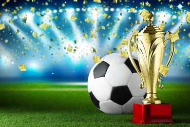 Image of Football championship. Shiny golden trophy cup and soccer ball under falling confetti on stadium