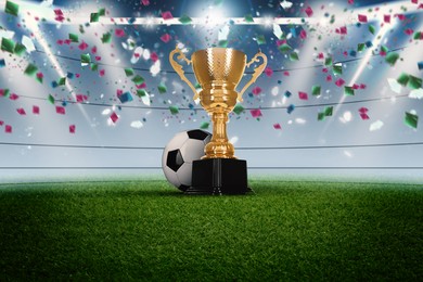 Image of Football championship. Shiny golden trophy cup and soccer ball under falling confetti on stadium
