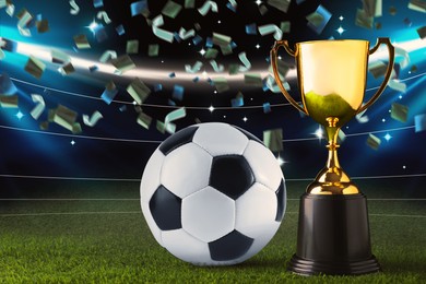 Image of Football championship. Shiny golden trophy cup and soccer ball under falling confetti on stadium