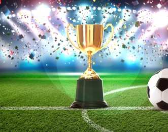 Image of Football championship. Shiny golden trophy cup and soccer ball under falling confetti on stadium