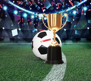 Image of Football championship. Shiny golden trophy cup and soccer ball under falling confetti on stadium
