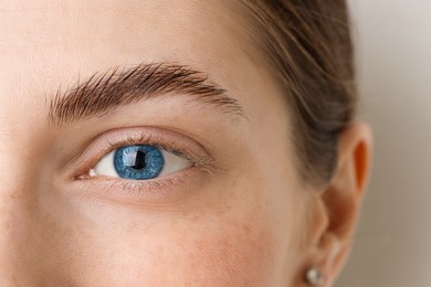Image of Closeup view of woman with blue eyes on beige background