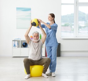 Photo of Doctor and patient exercising with medicine ball in clinic, space for text