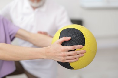 Photo of Doctor and patient exercising with medicine ball in clinic, closeup
