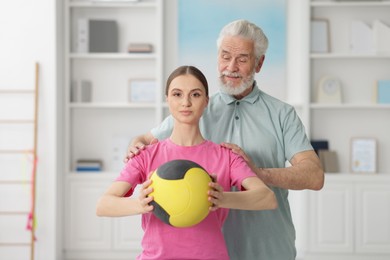 Photo of Doctor and patient exercising with medicine ball in clinic