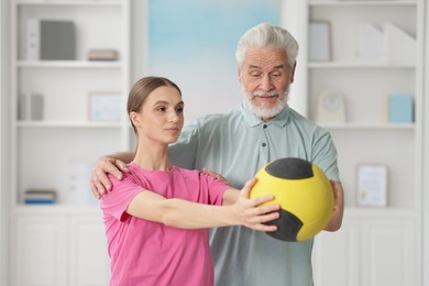 Photo of Doctor and patient exercising with medicine ball in clinic