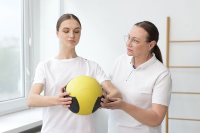 Photo of Doctor and patient exercising with medicine ball in clinic