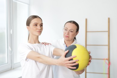Photo of Doctor and patient exercising with medicine ball in clinic