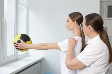 Photo of Doctor and patient exercising with medicine ball in clinic