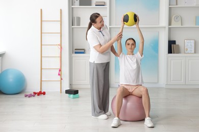Photo of Doctor and patient exercising with medicine ball in clinic