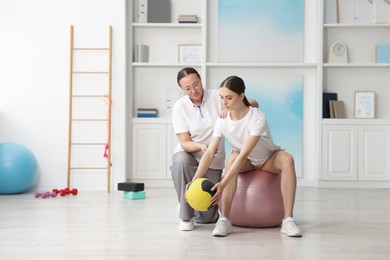 Photo of Doctor and patient exercising with medicine ball in clinic