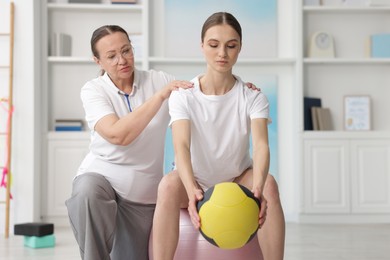 Photo of Doctor and patient exercising with medicine ball in clinic