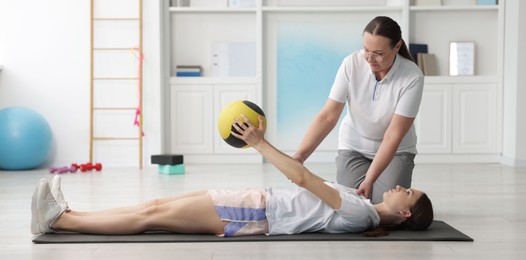 Photo of Doctor and patient exercising with medicine ball in clinic