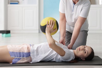 Photo of Doctor and patient exercising with medicine ball in clinic