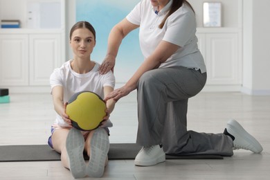 Photo of Doctor and patient exercising with medicine ball in clinic