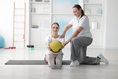 Photo of Doctor and patient exercising with medicine ball in clinic