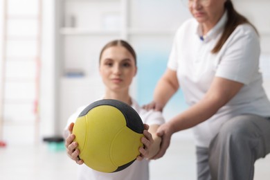 Photo of Doctor and patient exercising with medicine ball in clinic, selective focus
