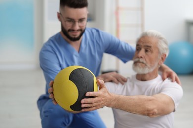 Photo of Doctor and patient exercising with medicine ball in clinic, selective focus