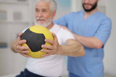 Photo of Doctor and patient exercising with medicine ball in clinic, selective focus