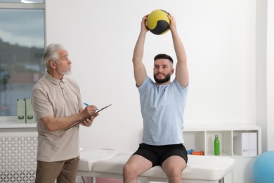 Photo of Doctor and patient exercising with medicine ball in clinic